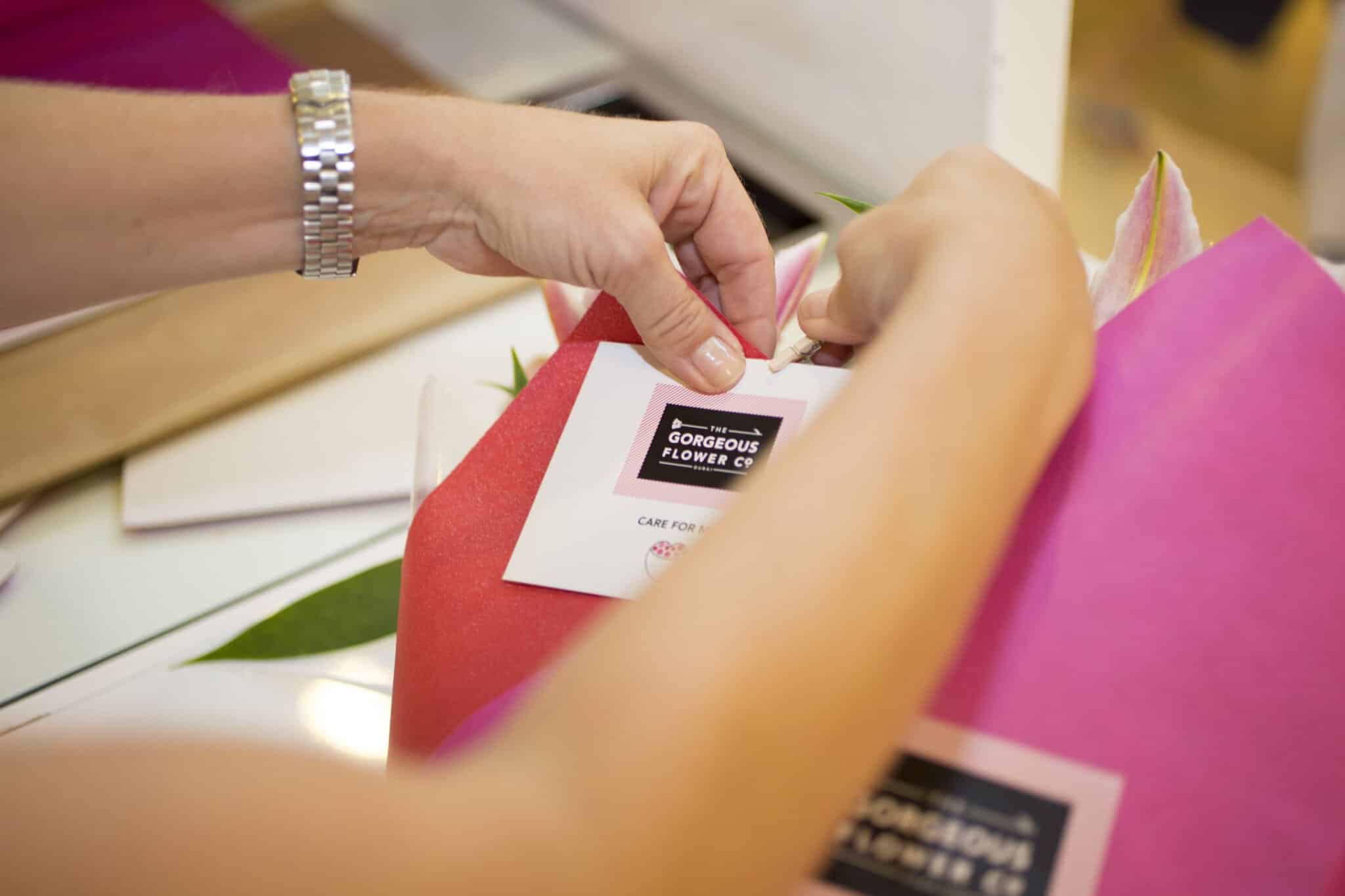 Sam pinning a care note for a customer to a bouquet of flowers